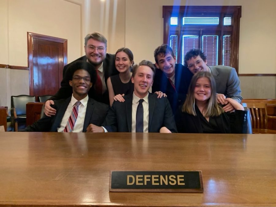 Mock trial team in suits with defense on table.