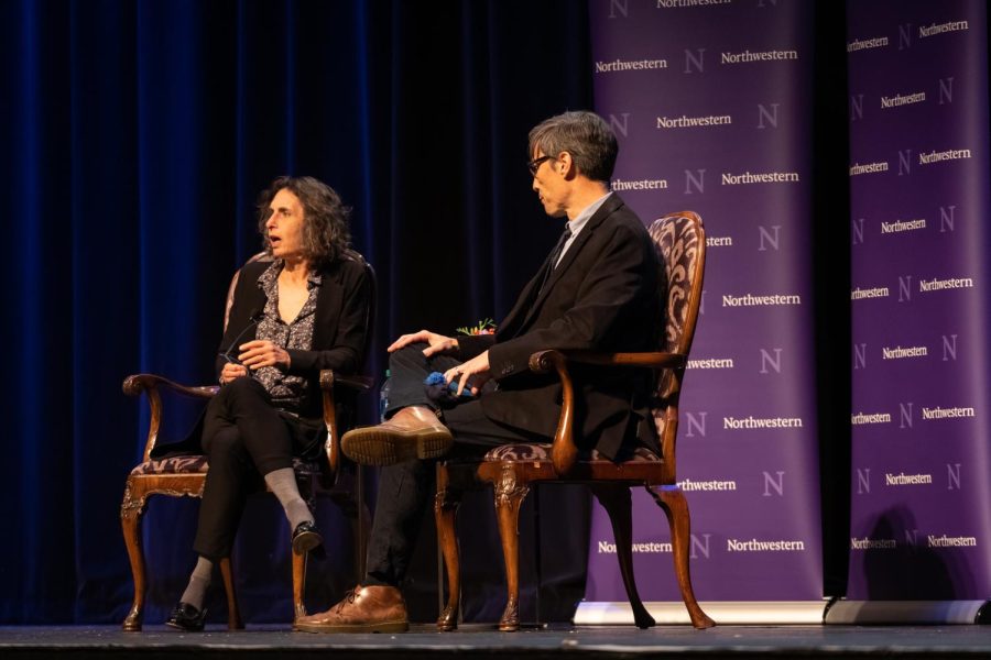 Two people sit in brown chairs on a stage with a purple “Northwestern” background.